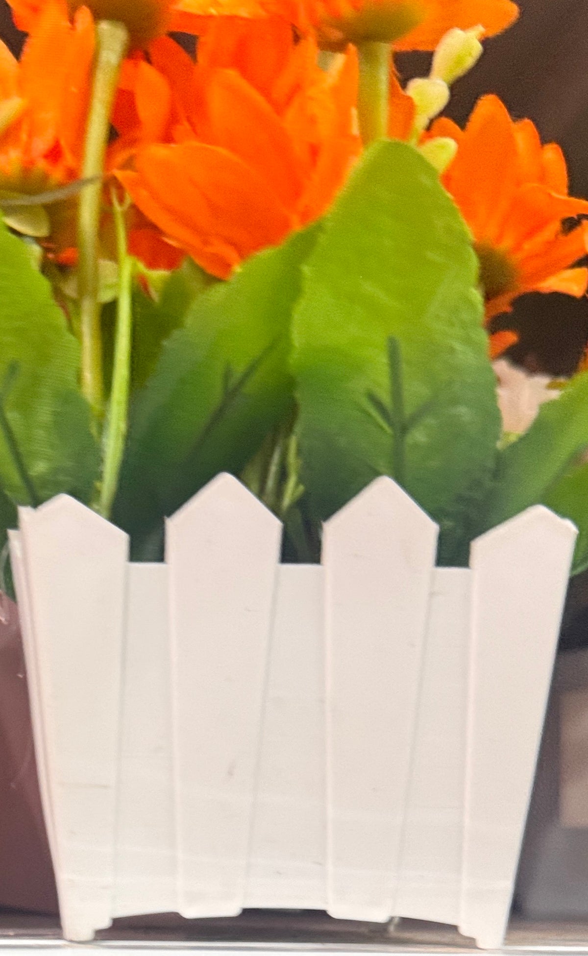 🌸 Planta Artificial con Gerberas Naranjas en Maceta Blanca Tipo Cerca de Madera · JL-15 - foto real 1